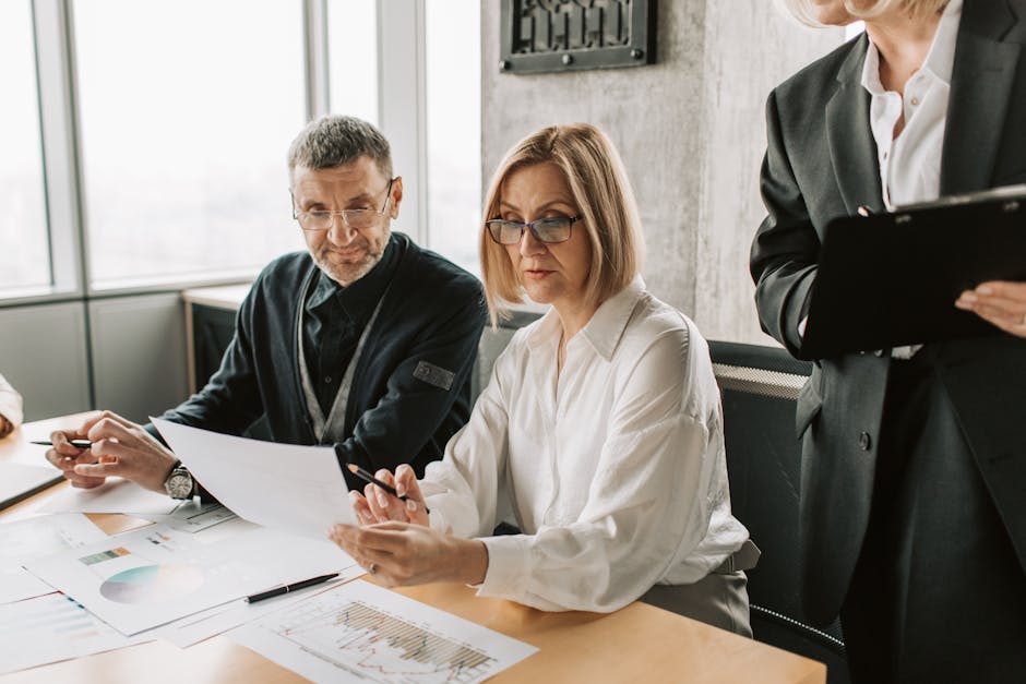 Business professionals engaged in a meeting, analyzing documents and charts in a modern office.